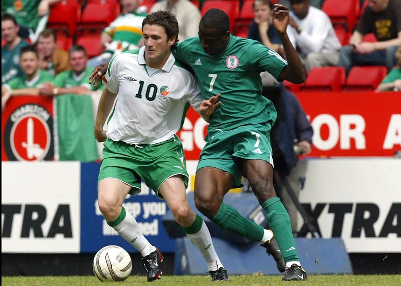 Robbie Keane shields the ball from John Utaka of Nigeria