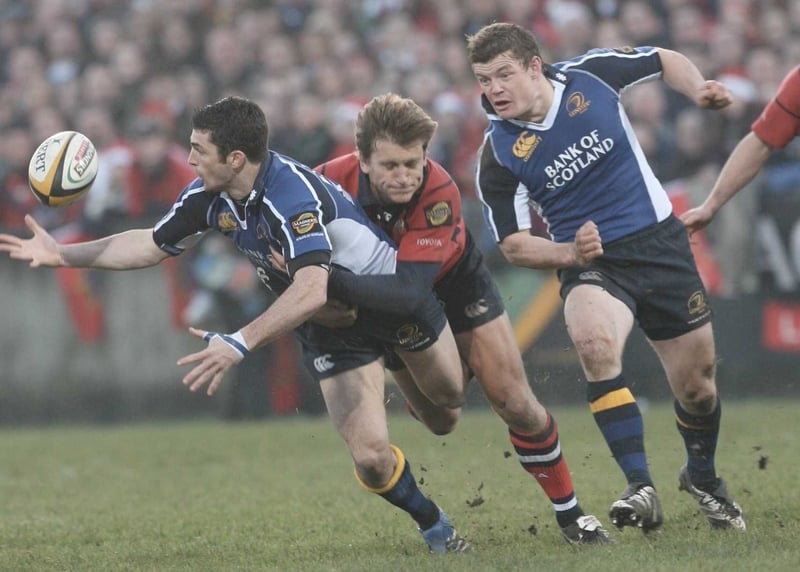 Leinster's Rob Kearney is tackled by Shaun Payne of Munster as Brian O'Driscoll looks on