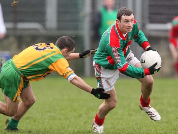 Keith Higgins of Mayo goes around Kevin McMenamin during their league meeting in February