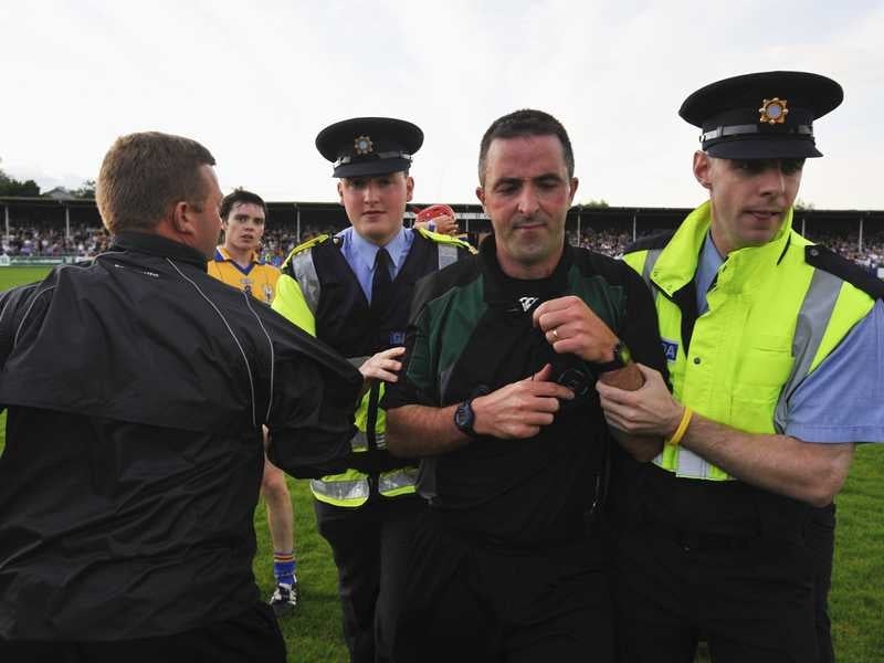 Referee Jason O'Mahony is escorted from the pitch by the gardaí