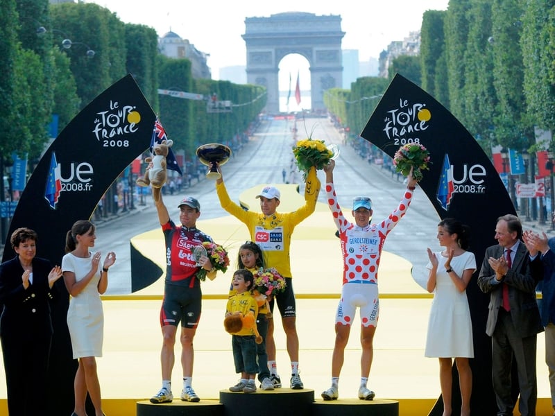 Carlos Sastre (centre) celebrates on the podium in Paris last year