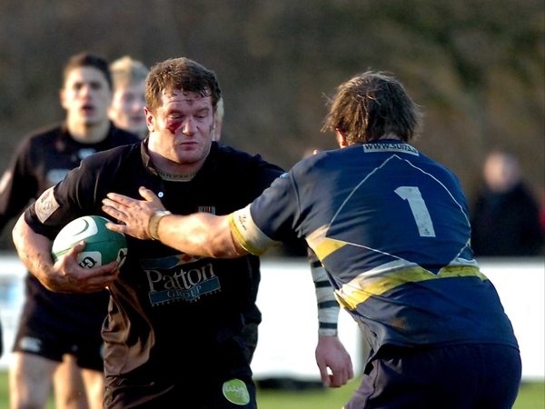 Sam McKinney of Ballymena fends off the challenge of Dolphin's Christy Condon
