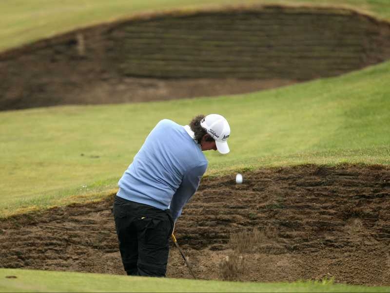 Rory McIlroy hits his approach shot from a fairway bunker the 11th green