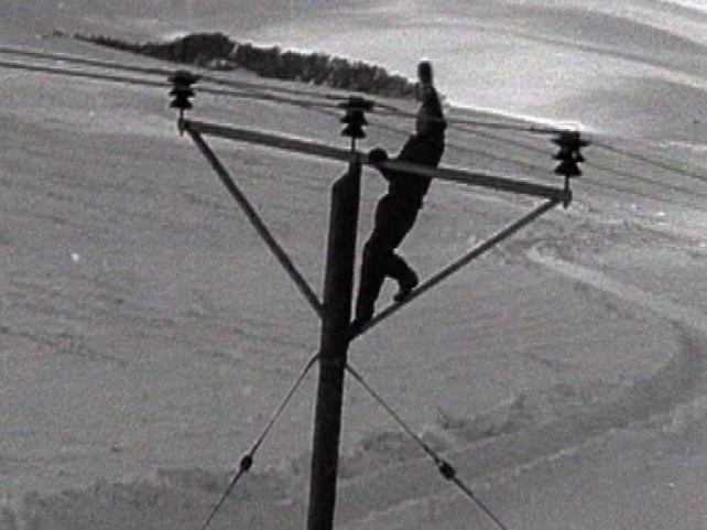 This man atop a telegraph pole gives some idea of how deep the drifts were in places.