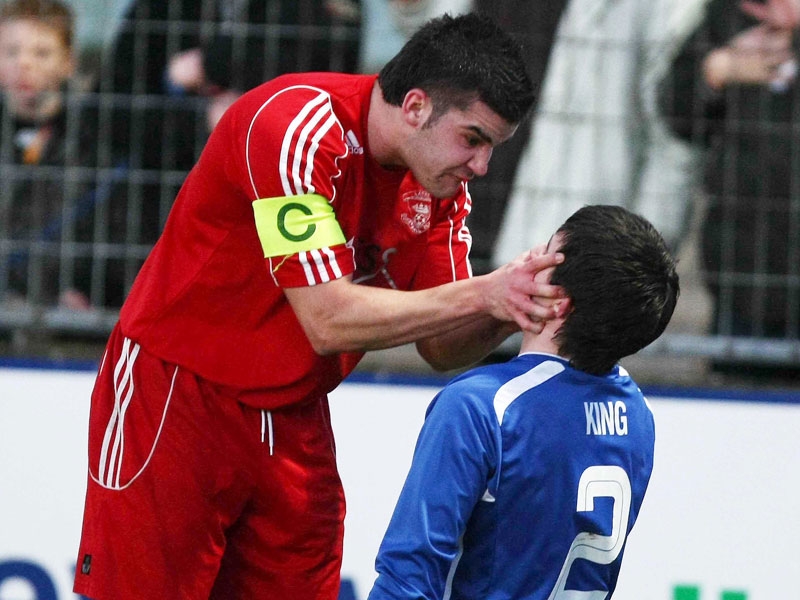 Larne captain Liam Hogan (red) confronts Newry City's Darren King (blue).