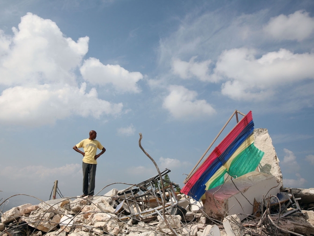 A man stands on the rubble of a collpased school in Petionville