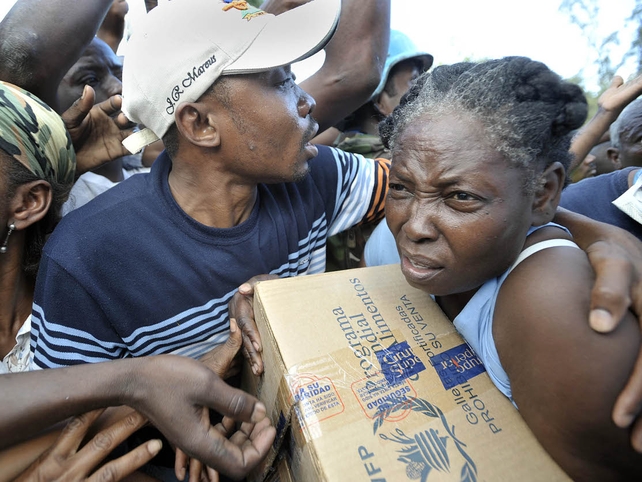 A woman tries to manoeuvre through a crowd after receiving a box of food at Park Boyer in Petionville