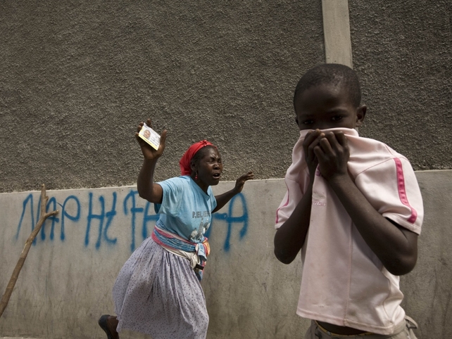 A child covers his nose as a woman mourns the dead