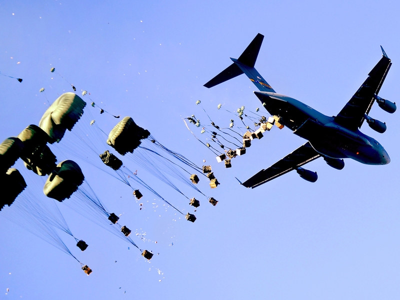 A US Air Force C-17 aircraft drops pallets of water and food over Mirebalais