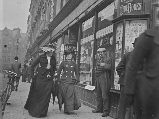Two women, one wearing necktie, walking on Grafton Street. Bystanders and shop-fronts visible in the background. Clarke Collection: 1890-1910