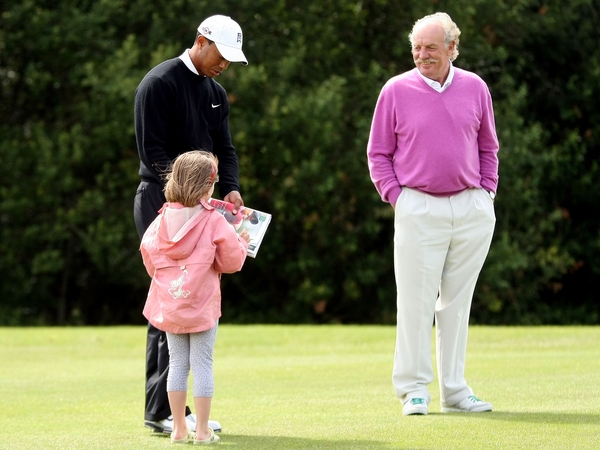 Tiger Woods signs an autograph for young fan Ava Mulhall on the seventh