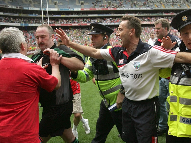 Louth manager Peter Fitzpatrick attempts to help usher referee Martin Sludden off the pitch as an angry spectator confronts the official