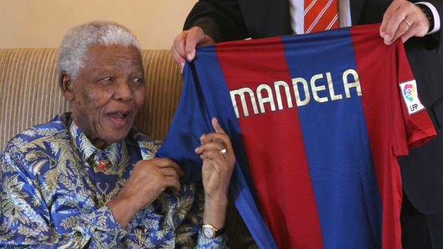 Nelson Mandela smiles as he receives a Barcelona Football Club jersey from club manager Albert Perrin at the Mandela foundation in Houghton on 20 June 2007