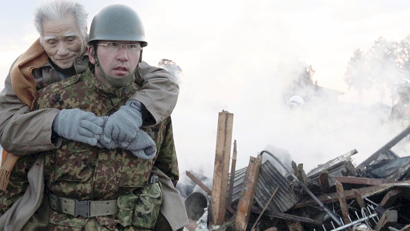 A soldier carries an elderly man on his back to a shelter in Natori city, Miyagi