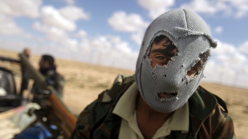 A Libyan rebel sits on the back of a pick-up truck as rebels gathered near Ajdabiya