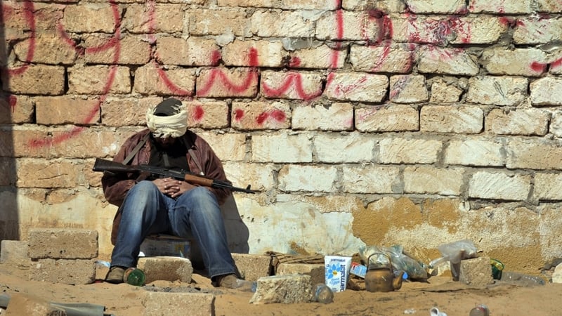 A rebel fighter rests at a checkpoint outside the city of Ajdabiya