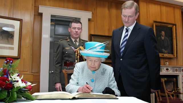 Taoiseach Enda Kenny watches as the Queen signs the visitor's book at Government Buildings