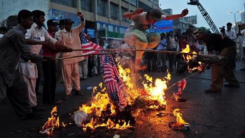 A man jumps over the burning effigy of US President Barack Obama during a protest rally in Karachi against US drone attacks in the country