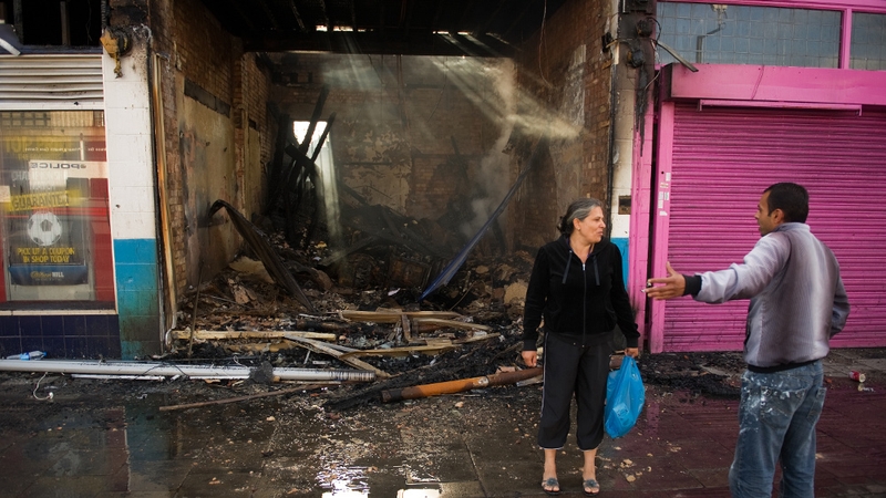 Local residents discuss events as they stand next to a destroyed shop