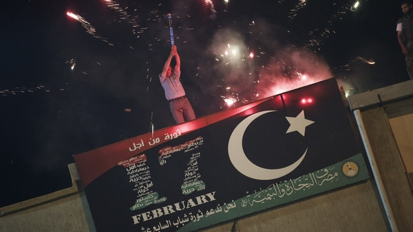 A Libyan man holds a flair on top of a building in Freedom square in Benghazi