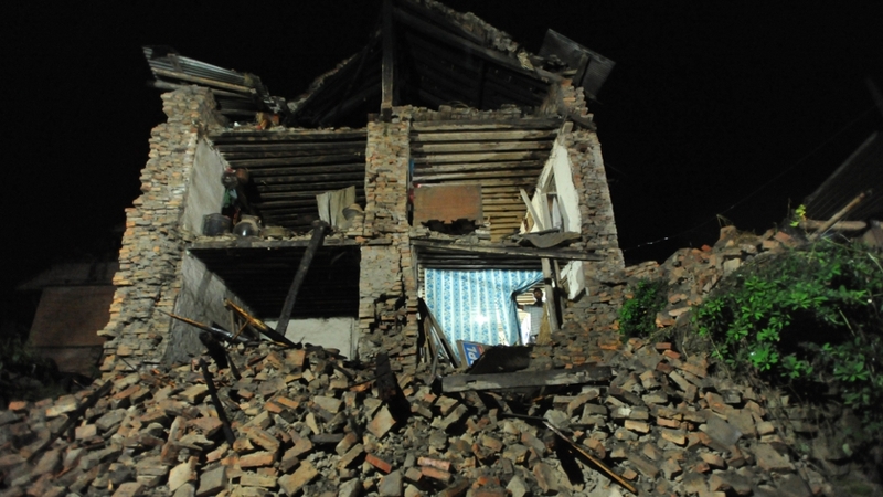 A man looks out a collapsed house damaged by an earthquake in Bhaktapur