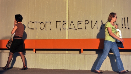 Two women walk past an anti-gay slogan in Belgrade