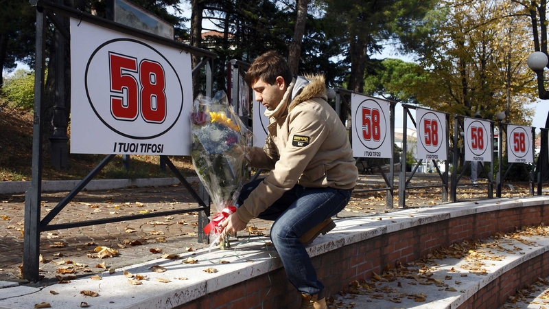 A fan of Marco Simoncelli lays flowers under his race number in Cattolica