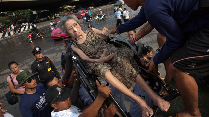 An elderly woman sits amongst Thai residents on crowded truck going toward a hospital in Bangkok