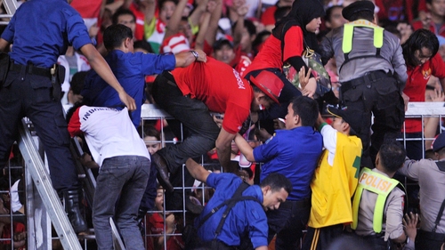 Stadium tragedy - Police and security staff help fans over barriers inside the overcrowded arena in Jakarta