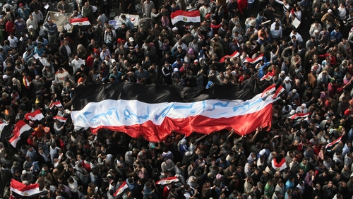 Demonstrators hold a huge national flag with the slogan 'Leave, Egypt is bigger than all of you' written in Arabic