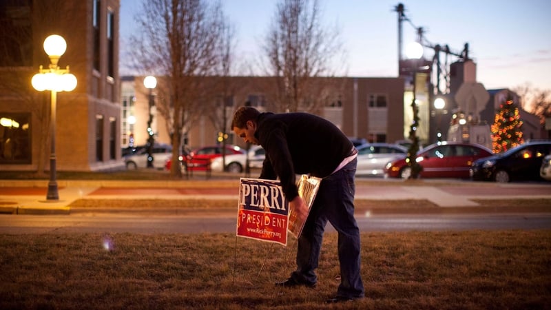 A supporter of Texas Governor and Republican presidential candidate Rick Perry places campaign ads before an event in Iowa