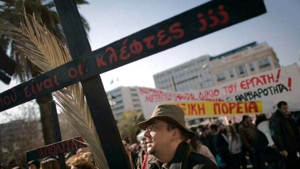 A man holds a wooden cross asking 'Where are the Thieves' during a strike