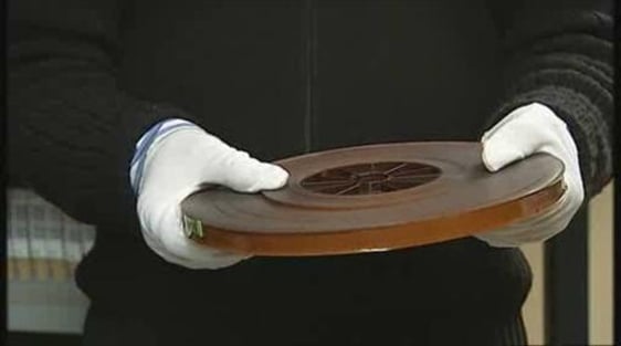 An archivist holds a roll of 16mm magnetic film track.