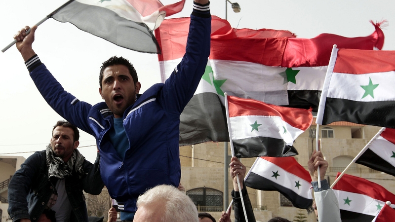 A Syrian living in Jordan waves his national flag as he takes part in a demonstration in support of Syrian President Bashar al-Assad outside the Syrian embassy in Amman
