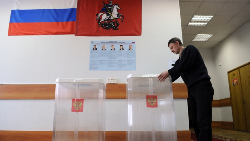 An election official adjusts a ballot box at a polling station in Moscow