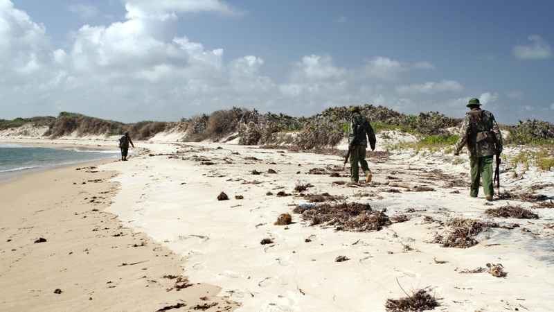 Armed police men patrol a stretch of beach near Kiwayu Safari village in Kenya where David and Judith Tebbutt were attacked