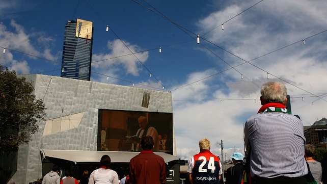 Crowds watch the service on a big screen at Federation Square