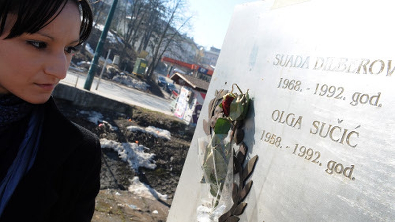 A local woman looks at a plaque in memory of the first two war victims at a bridge in central Sarajevo