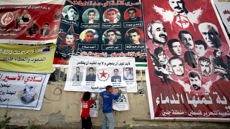 Palestinian children in the northern West Bank village of Araba, near Jenin, add pictures to a wall covered in posters of Palestinians held in Israeli jails