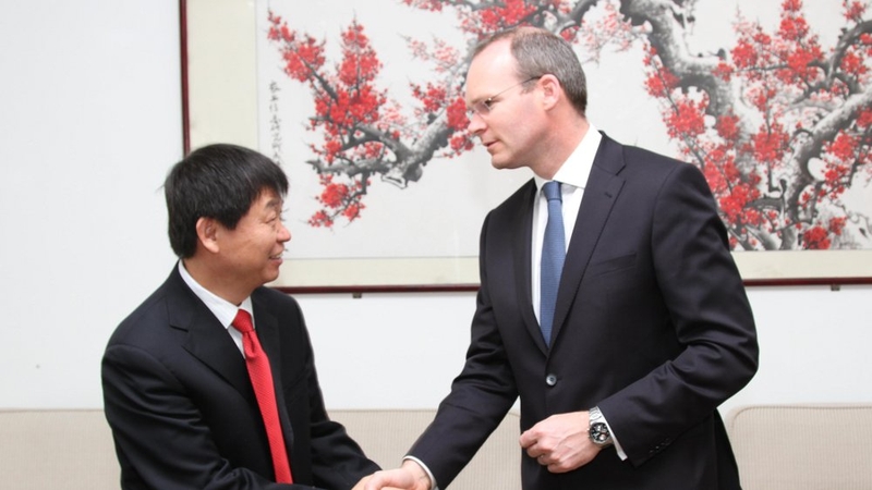 Simon Coveney is greeted by the Chair of the Sino Irish Forum, Prof Jiayang Li