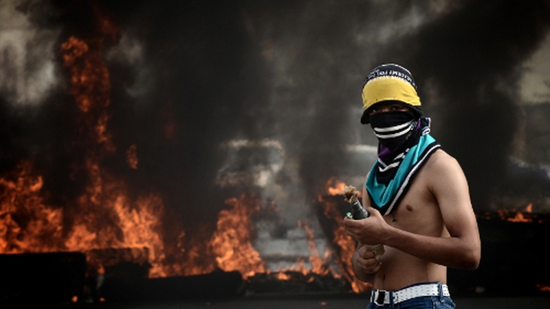 A protester lights a petrol bomb near a police barricade in Manama