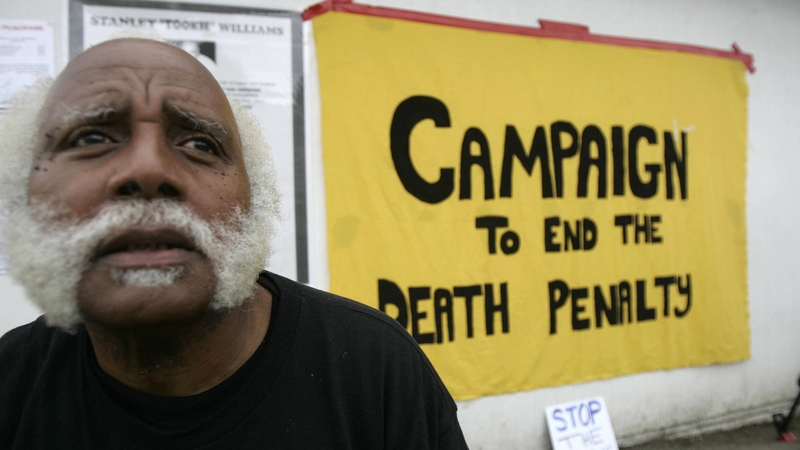 An anti-death penalty activists sits near a sign at the entrance of San Quentin State Prison in 2005