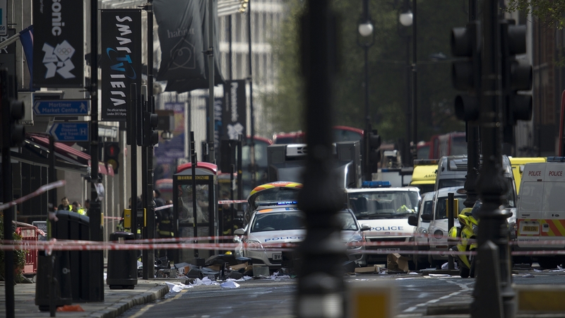 Debris litters the pavement and road in front of police vehicles below the office building