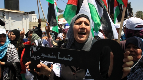 A woman holds a key saying 'Haifa, we will return for sure'