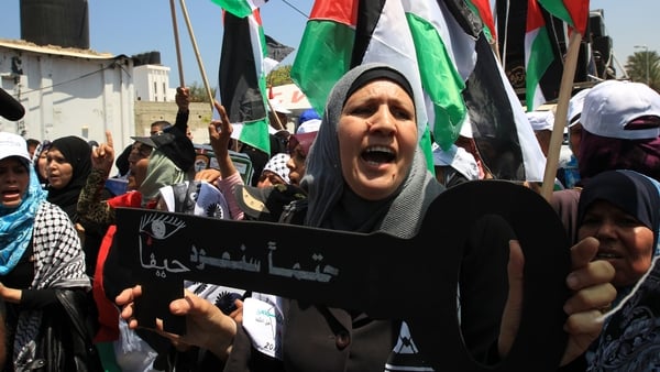 A woman holds a key saying 'Haifa, we will return for sure'