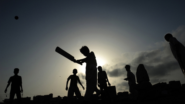 Pakistani youths play cricket at a slum area of Karachi