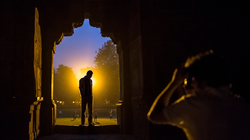 A boy has his photo taken by a friend as he stands in an archway of the Bara Gumbad, the tomb of Sikander Lodi, in New Delhi, India