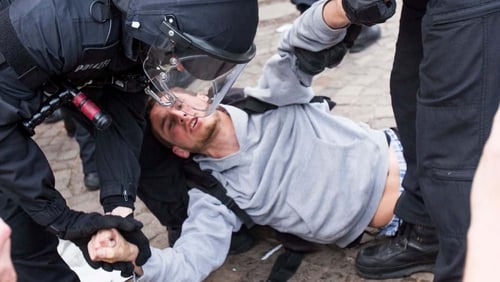 German riot police carry a protester after the dissolution of an unauthorised rally in front of city hall