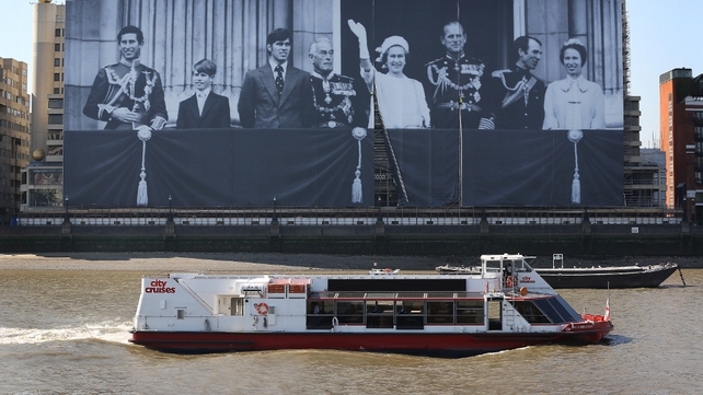 Workers erect a giant photograph of the British Royal family on a building on The River Thames in London, England