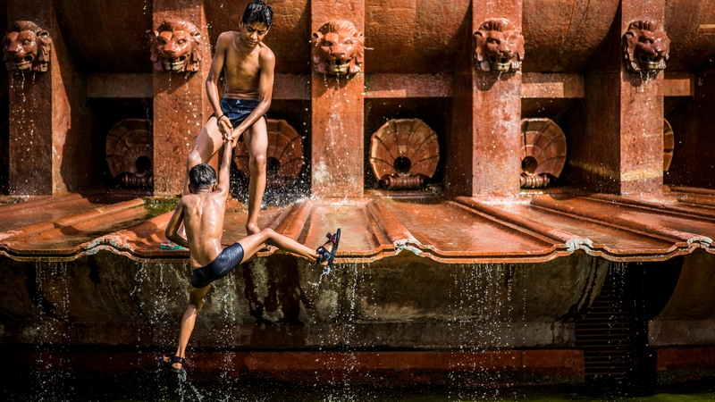Boys escape 40C heat by playing in a fountain at India Gate monument in New Delhi, India
